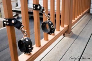 A pair of leather bondage cuffs attached to a balcony railing