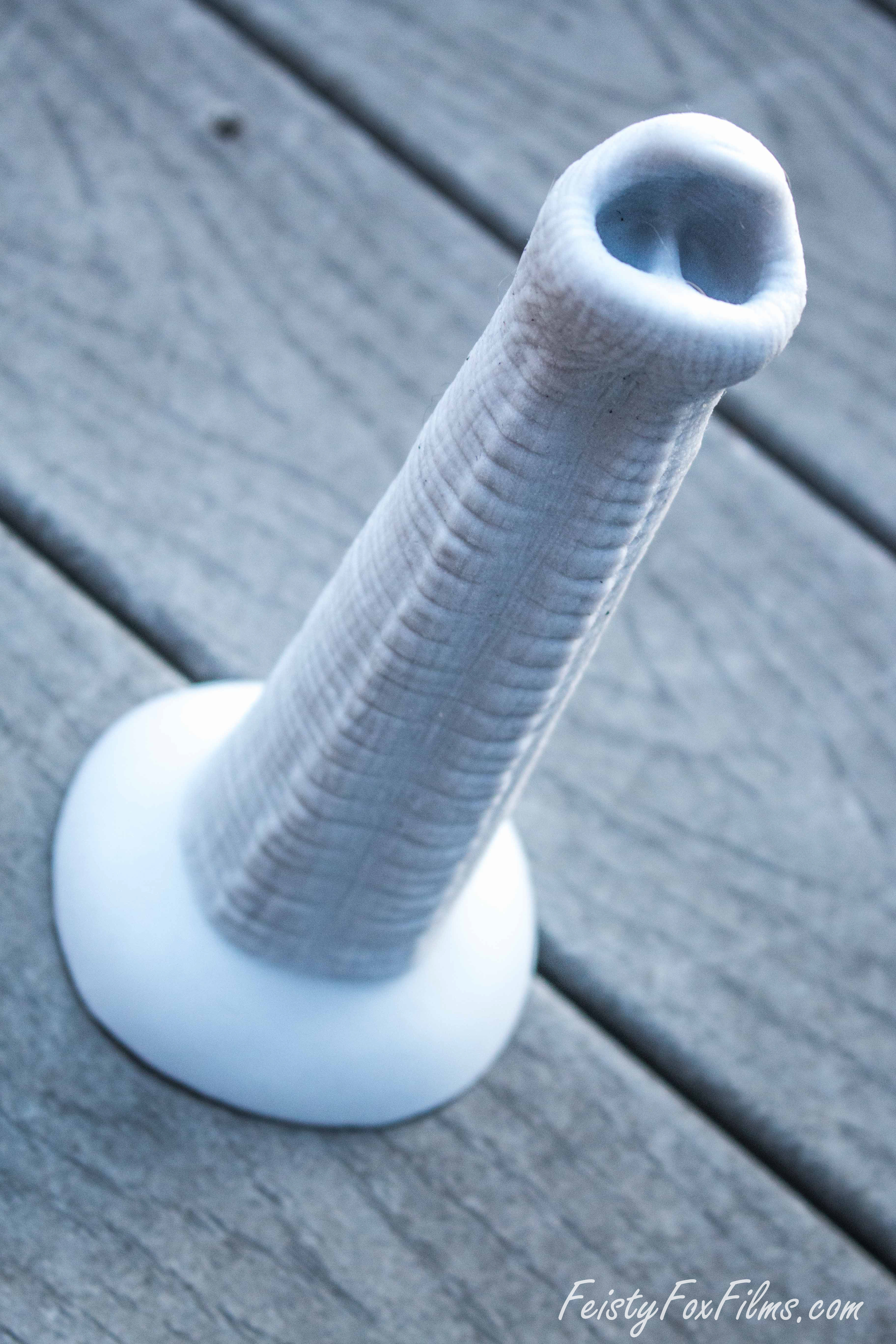 Exotic Erotics Elephant Trunk dildo lying on a wooden deck. It is lying diagonal from the bottom left to the upper right corner, showing the deep indents in the nose