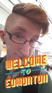 Taylor smirks sleepily at the camera. A brightly-coloured pop art filter is across the bottom of the image saying "Welcome to Edmonton" on it