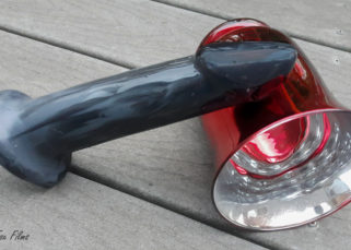 Servant Sex Toy's Lune sits on a deck at an angle, the head resting on a red bell-shaped plant holder. The colours in the Lune are more muted from this angle, but you can still see a lot of variation.