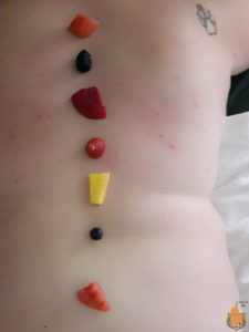 A row of fruit going down the bare skin on Indigo's spine.