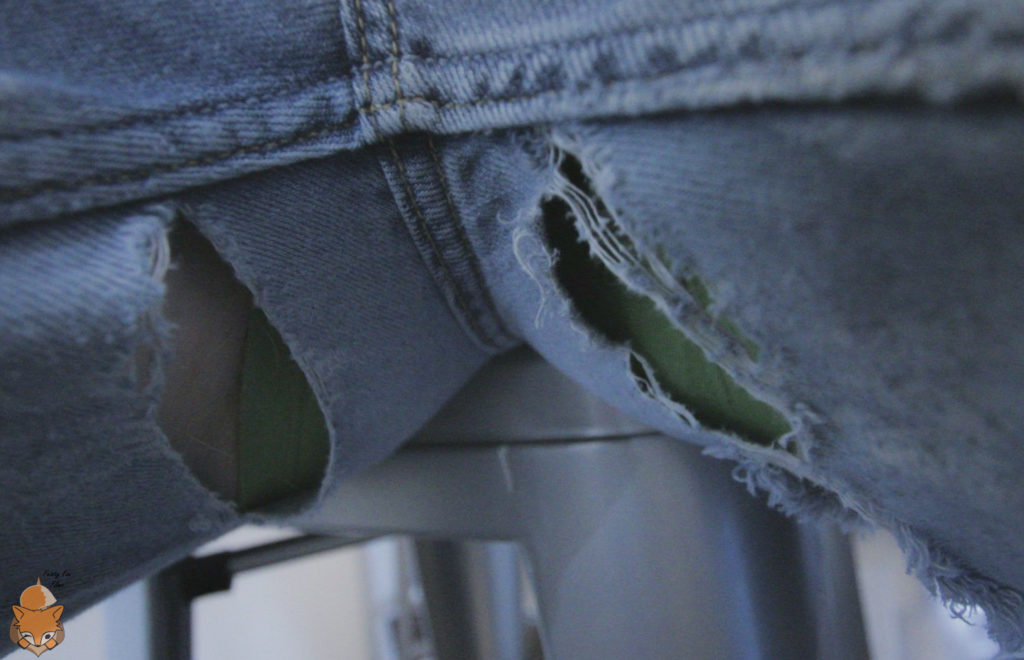 Spread legs. There are large holes in the inner thighs of the jeans